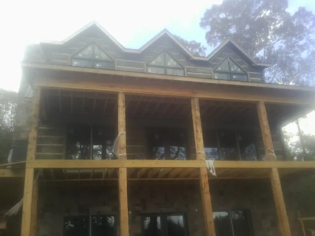 Dormers and porch framing on a large log home under construction — Roof Coating work by our crew in Prosperity